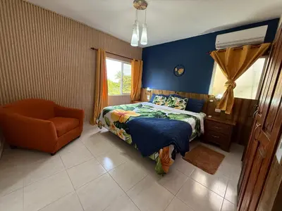 a bedroom with a bed and a chair and a window at Brisa de mar in San Felipe de Puerto Plata