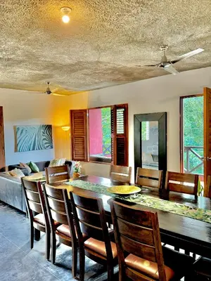 a dining room with a table and chairs and a couch at Hostal Luz Del Valle in Santa Bárbara de Samaná