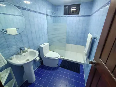 a blue tiled bathroom with a toilet and a sink at Comfortable and quiet double room in Santo Domingo