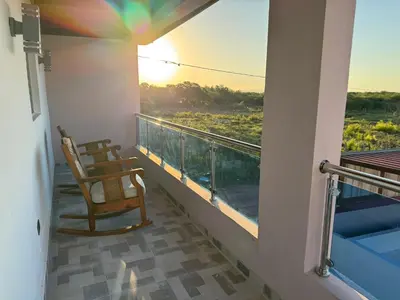a balcony with a chair and a view of the sunset at Terra Mia Villa in Pedernales
