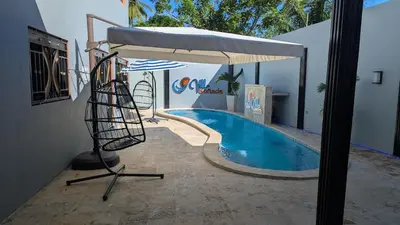 a swimming pool with an umbrella and a chair next to it at Villa soñada 1 in Sosua