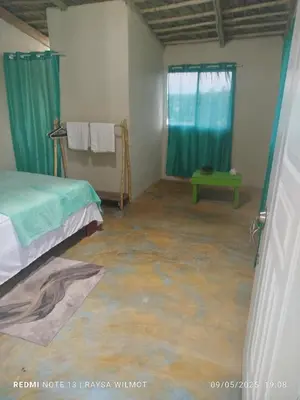 a bedroom with a concrete floor and blue curtains at Parador tropical in Las Galeras