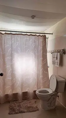 a bathroom with a toilet and a shower curtain at Garden Mar in Bonao
