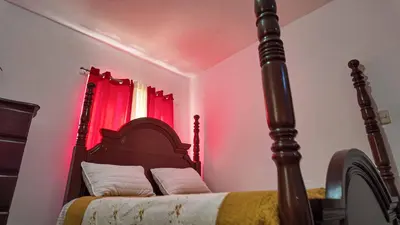 a bedroom with a bed with a red curtain at Garden Mar in Bonao
