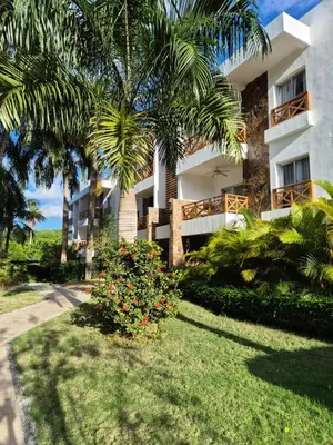 a building with palm trees in front of a yard at Jardines de Montserrat - Lux, Rooftop, 3Bds, near beach in Las Terrenas
