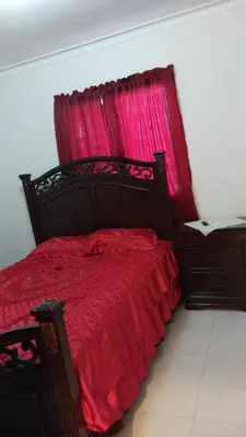 a bedroom with a red bed with a red curtain at This beautiful apt you can have a nice vacation in Santo Domingo