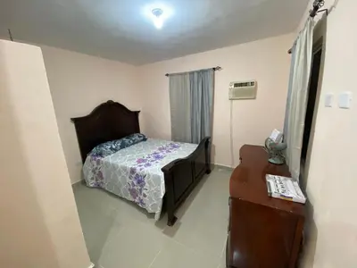 a bedroom with a bed and a dresser and a table at Casa amarilla in La Romana