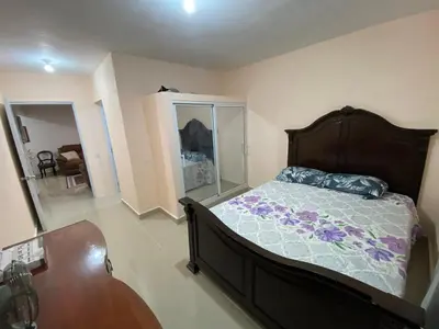 a bedroom with a bed and a dresser and a table at Casa amarilla in La Romana