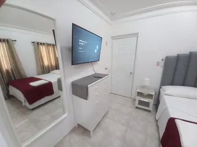 a bedroom with a tv and a bed and a mirror at Casa Petter and Maria, 2end floor in Santiago de los Caballeros