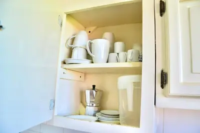 a cupboard filled with dishes and cups and plates at Cozy apartment - steps from Playa Costambar in San Felipe de Puerto Plata