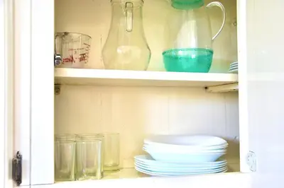 a cabinet filled with plates and bowls and glasses at Cozy apartment - steps from Playa Costambar in San Felipe de Puerto Plata