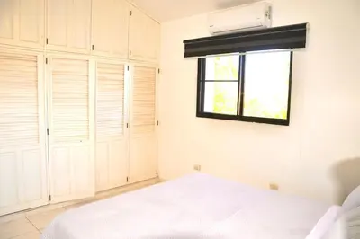 a bedroom with white cabinets and a window at Cozy apartment - steps from Playa Costambar in San Felipe de Puerto Plata