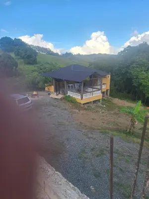 a house on a hill with a car in front of it at Caribbean Corner in Jarabacoa