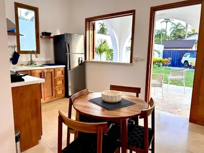 a kitchen with a wooden table with chairs and a kitchen with a refrigerator at Villa Coral Blue in Playa Bonita in Las Terrenas