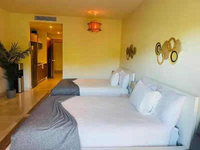 a hotel room with two beds and a couch at Modern 2 Queen Beds Apartment with Garden View in Puerto Plata