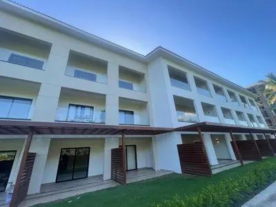a white building with a lawn in front of it at Modern 2 Queen Beds Apartment with Garden View in Puerto Plata