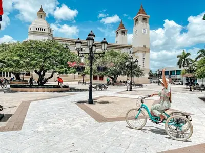a woman riding a bike in front of a building at impecable 2 Bedroom Apartment Steps from the Pier in San Felipe de Puerto Plata