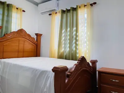 a bedroom with a wooden bed and curtains at impecable 2 Bedroom Apartment Steps from the Pier in San Felipe de Puerto Plata