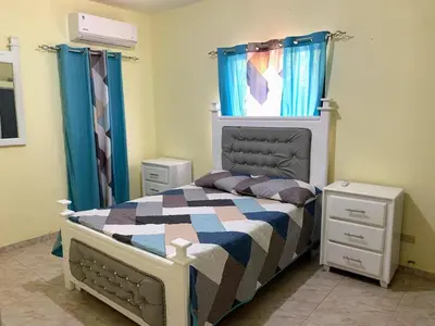 a bedroom with a bed and blue curtains at Tu Casa En Pedernales in Pedernales