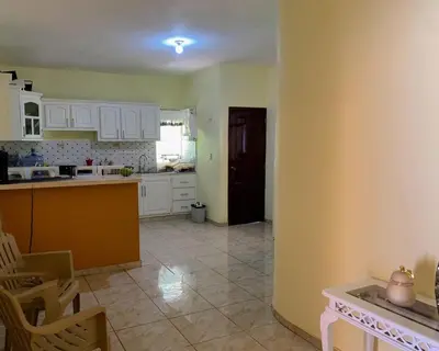 a kitchen with yellow walls and white cabinets and a table at Tu Casa En Pedernales in Pedernales
