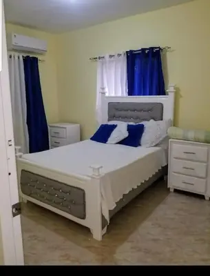 a bedroom with a white bed with blue curtains at Tu Casa En Pedernales in Pedernales