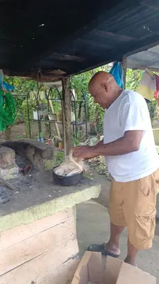 a man cooking food in a pan on a stove at las taranas villa tropical