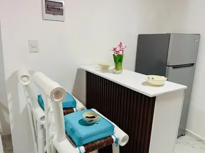 a kitchen with a chair with a table and a refrigerator at Sabor Latino Apartment in San Felipe de Puerto Plata