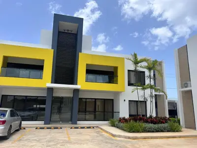 a yellow and white building with a car parked in a parking lot at jardines de caleta in La Romana