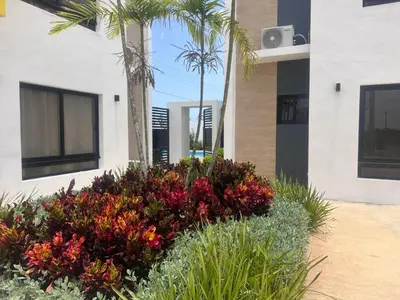 a garden with flowers and palm trees in front of a building at jardines de caleta in La Romana