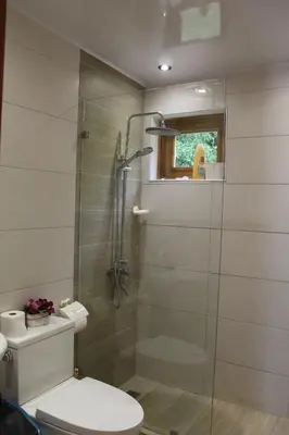 a bathroom with a toilet and a glass shower at Villa refugio de paz in Bayaguana