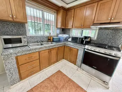 a kitchen with wooden cabinets and a stove top oven at Charming villa in San Pedro de Macorís