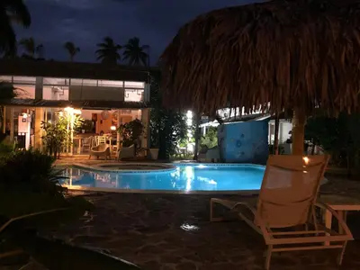 a chair next to a swimming pool at night at Cosy Apartment 1 bedroom, swimming pool and beach 30m in Las Terrenas