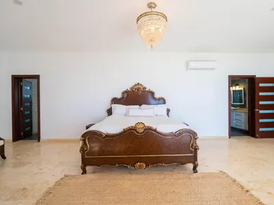 a large bed in a room with a chandelier at Villa Emoción Del Mar - Beachfront Luxury Villa