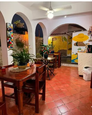 a dining room with tables and chairs and a kitchen at Hotel Montesilva in Puerto Plata