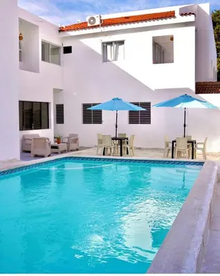 a swimming pool with chairs and umbrellas next to a house at Hotel Montesilva in Puerto Plata
