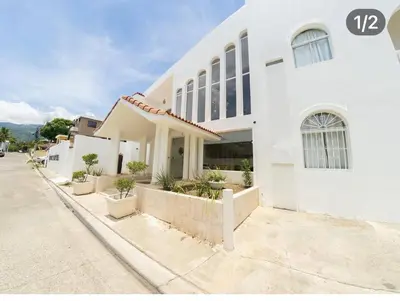 a white building with potted plants next to a street at Hotel Montesilva in Puerto Plata