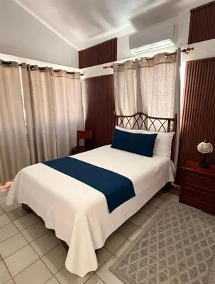 a bedroom with a large bed with blue and white sheets at Hotel Montesilva in Puerto Plata