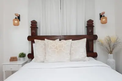 a bed with a wooden headboard and white pillows at Rustic Charm, Apartment in the heart of Santiago in Santiago de los Caballeros