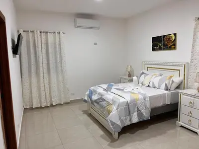 a white bedroom with a bed and a window at Residencial Torre del Atlantico in Puerto Plata
