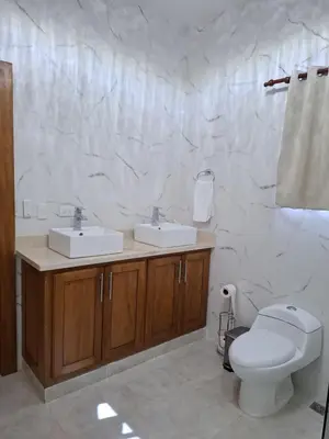 a white bathroom with two sinks and a toilet at Villa with Pool Terrace and 3 minutes to the beach in Puerto Plata