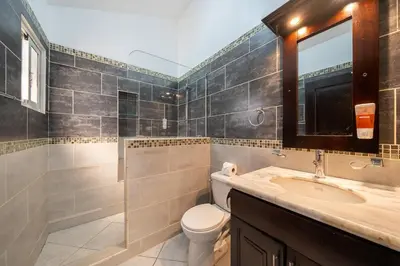 a bathroom with a toilet and a sink and a mirror at 6BR, Jacuzzi, Ocean View, Solar Backup Power in Sosúa
