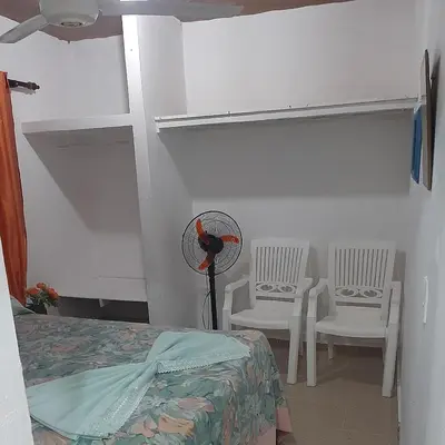 a bedroom with a bed and two chairs and a fan at B&B KeisyAlba Punta Rucia in Punta Rucia