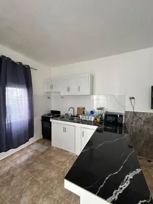 a kitchen with white cabinets and a black counter top at Residencial JG in Punta Cana
