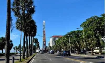 a street with palm trees and a tall building at City Sea Exclusive Colonial Gem with Ocean View in Santo Domingo