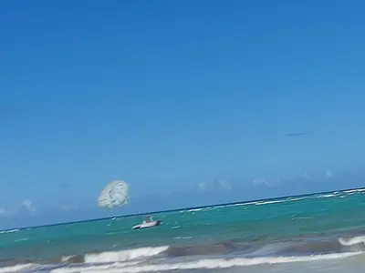 a person on a surfboard in the ocean with a kite at Residencial El Carey in Punta Cana
