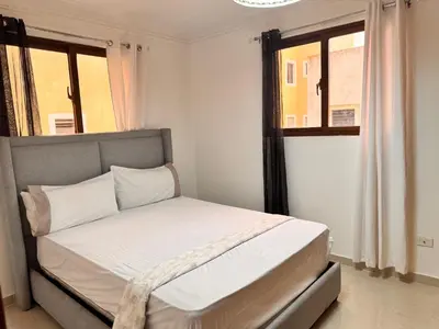a bedroom with a bed with white sheets and a window at Santiago Amazing 4bedrooms Apt for group, spectacular WIFI, close to all fun in Santiago de los Caballeros