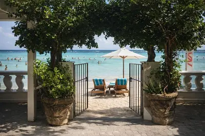 a beach with chairs and an umbrella and the ocean at Hotel Don Michele in Boca Chica