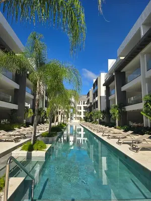 a swimming pool with chaise lounge chairs next to a building at Apartamento a estrenar con acceso privado a la playa in Punta Cana