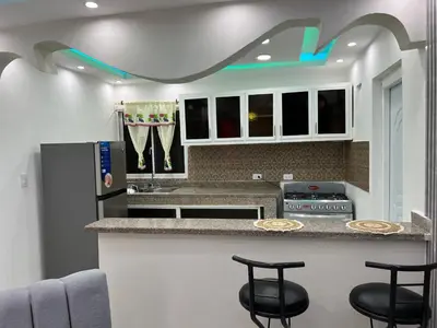 a kitchen with a counter with stools in it at Lujoso apartamento cerca del aeropuerto SDQ in La Caleta