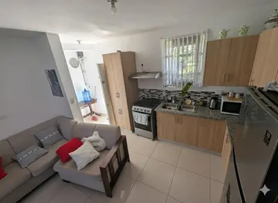 a living room with a couch and a kitchen at Elegant apartment within a gated residential complex- 10 mins from Cabarete in Gaspar Hernández